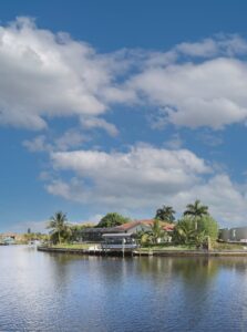 green trees near body of water under blue sky and white clouds in Naples which is  one of the Hottest Up and Coming Cities in the United States