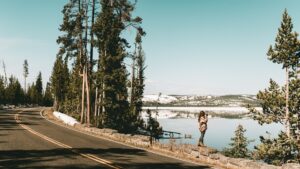 a woman taking photos by a lake in a winter landscape as the first in the list of safest and cheapest places to live in America